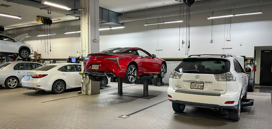 4 white cars and 1 red car in a mechanic shop